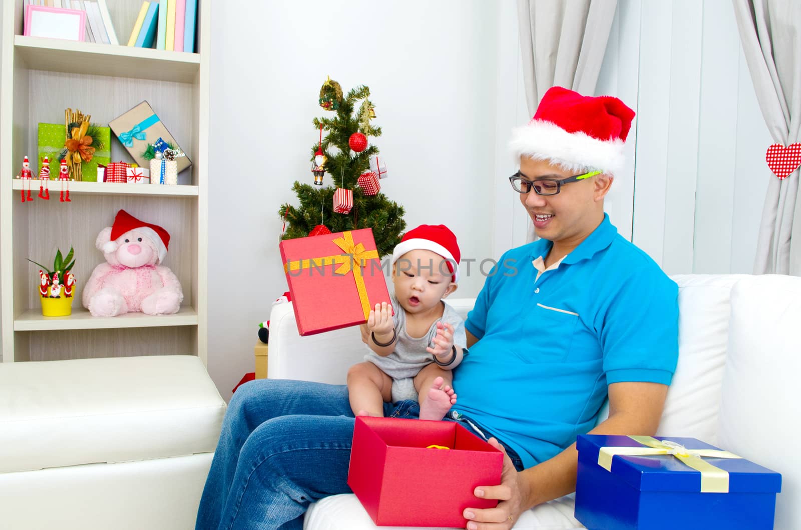 Portrait of happy father and his son in Santa caps on Christmas eve