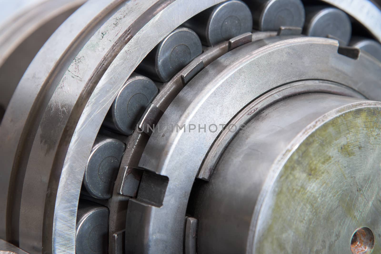 Stainless roller bearing on industrial size drive shaft. Shallow depth of field with only parts of the bearing in focus.