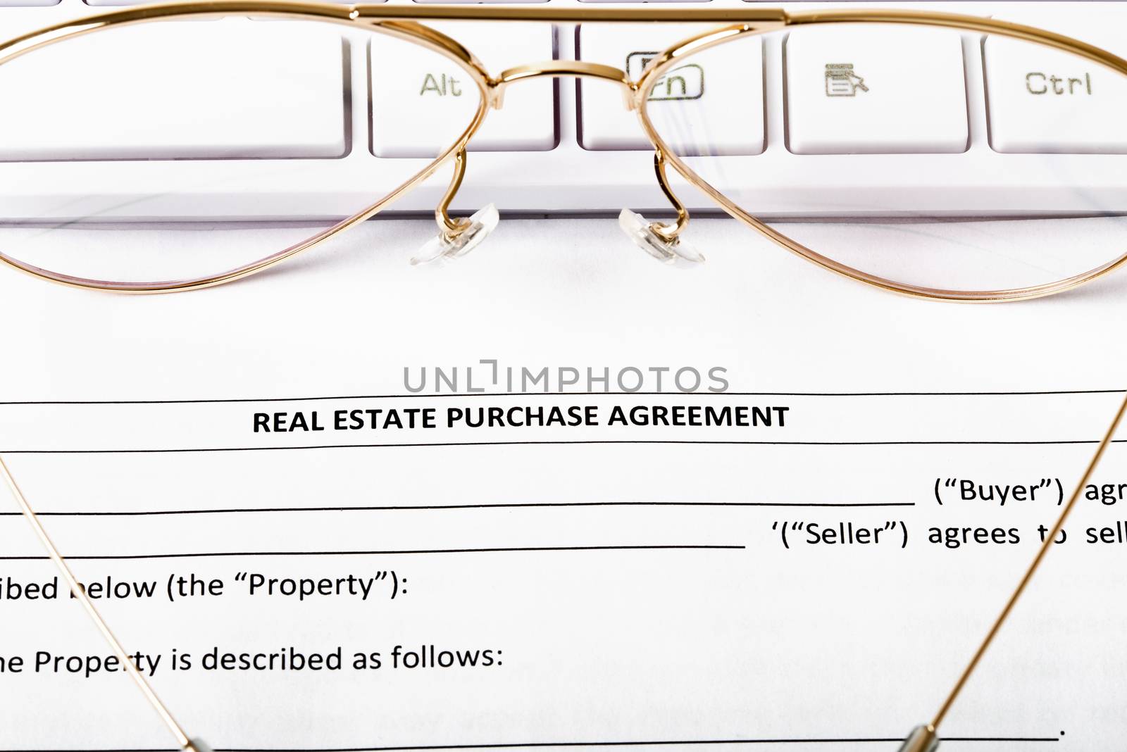 Keyboard with eyeglasses and real estate purchase agreement
