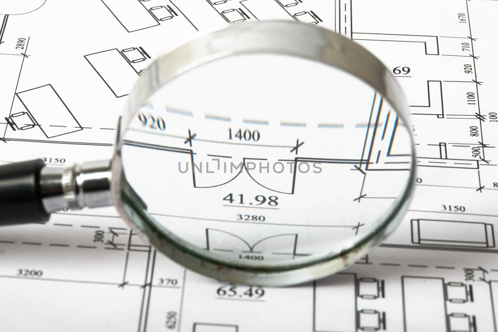 Magnifier on blueprints with figures, close up view