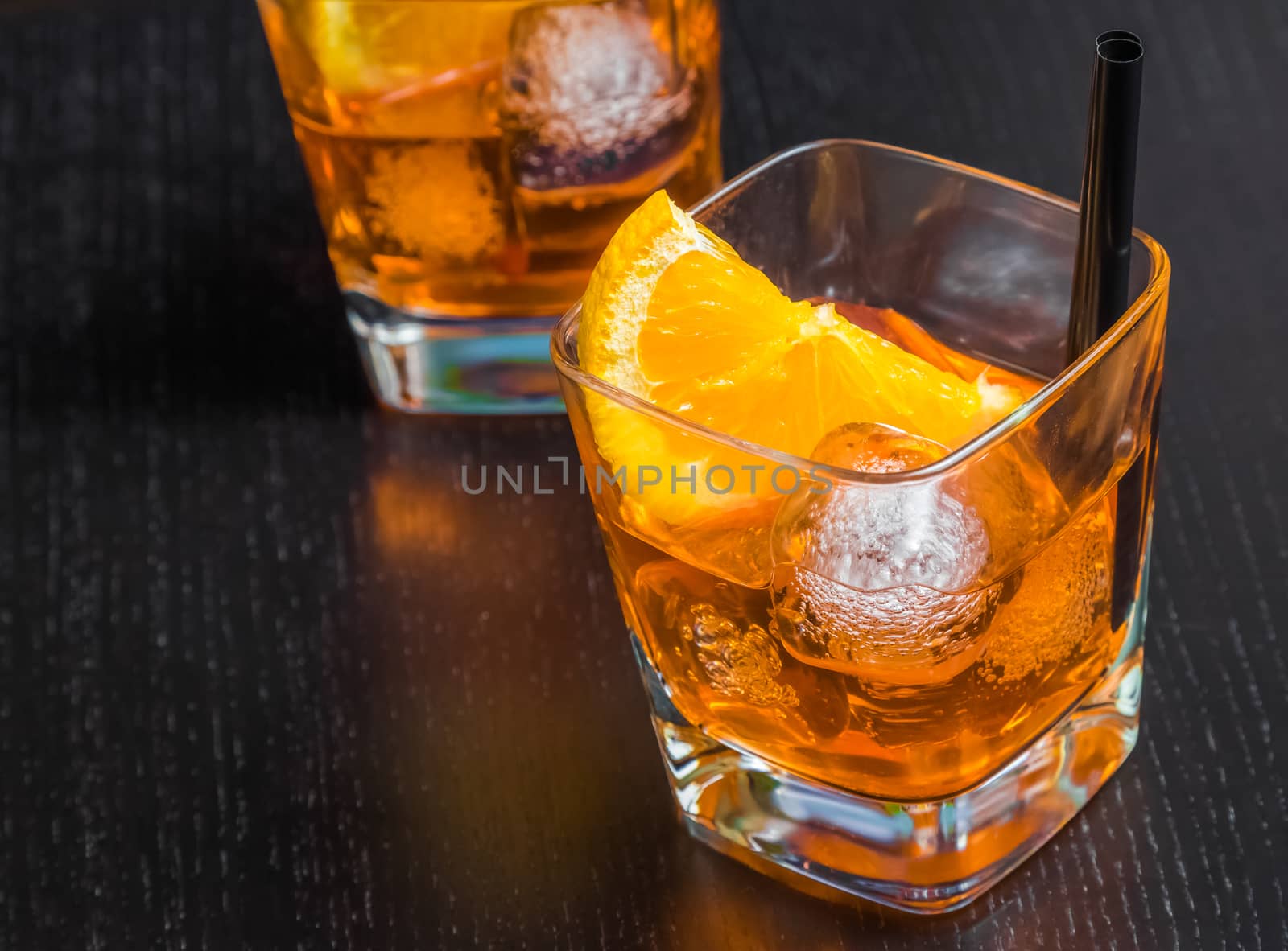 two glasses of spritz aperitif aperol cocktail with orange slices and ice cubes on wood table