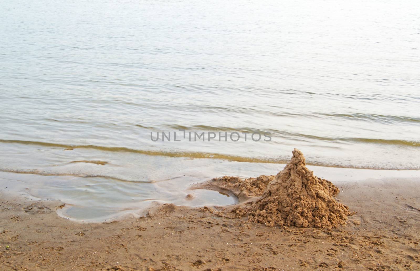 Heap of clean sand shaped as a castle on sea beach