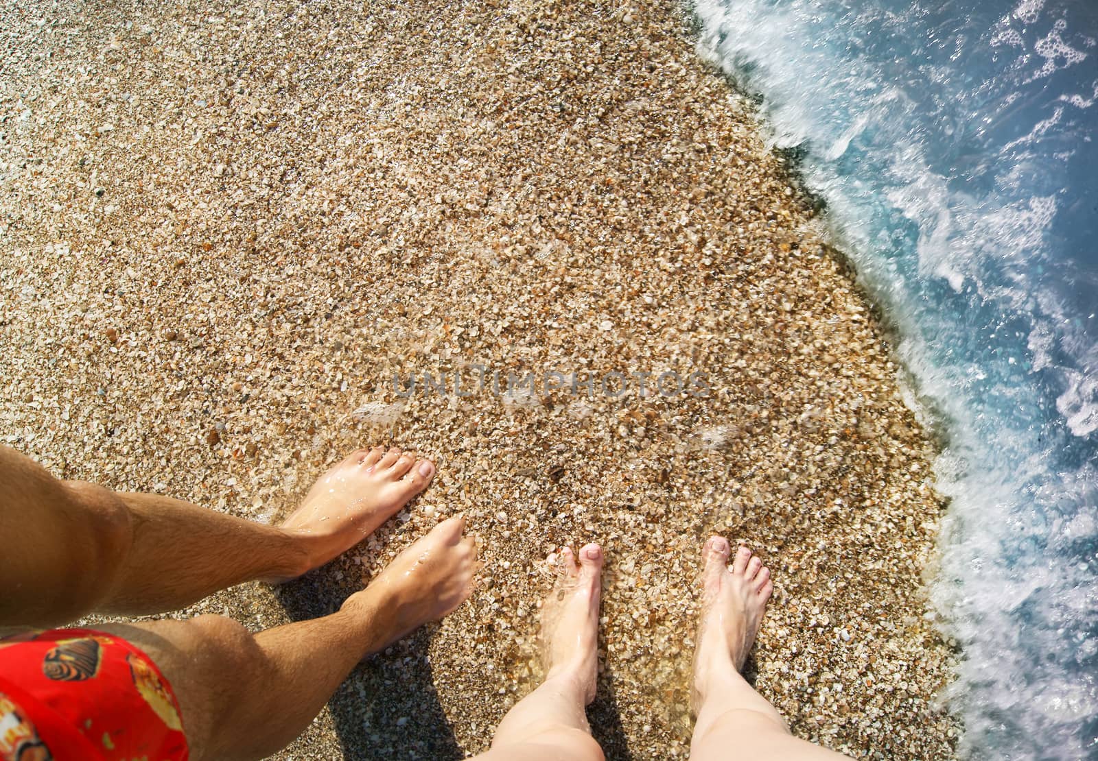 View on shoeless feet of a man and a girl in the water