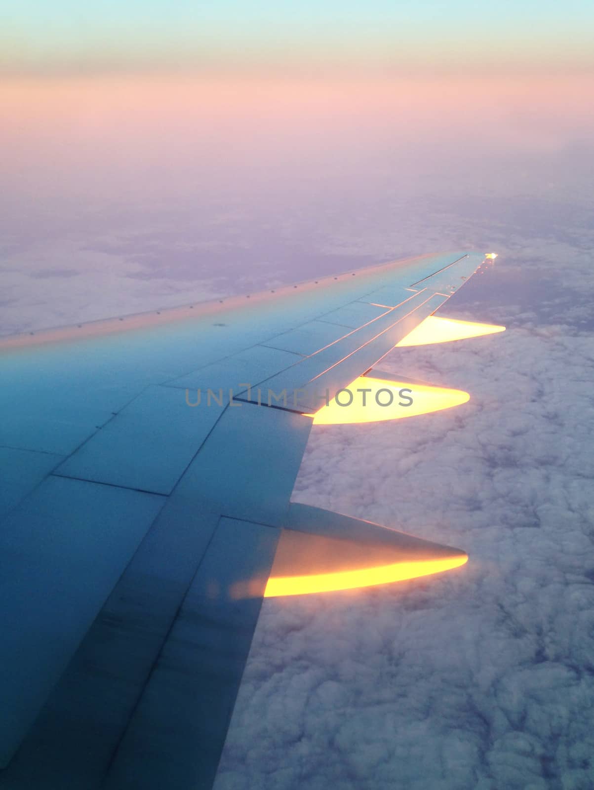 Shot from the flying plane of its wing lighted with sun at sunset