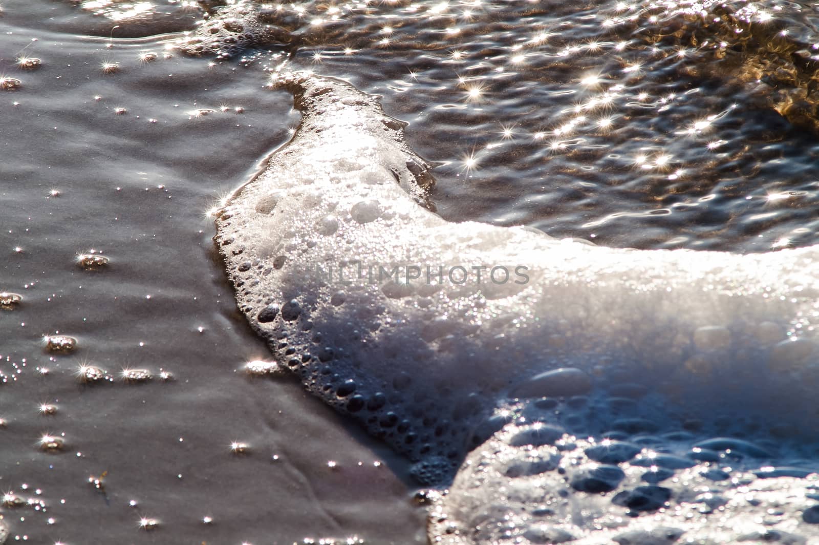 surf on a sandy beach with waves at sunset