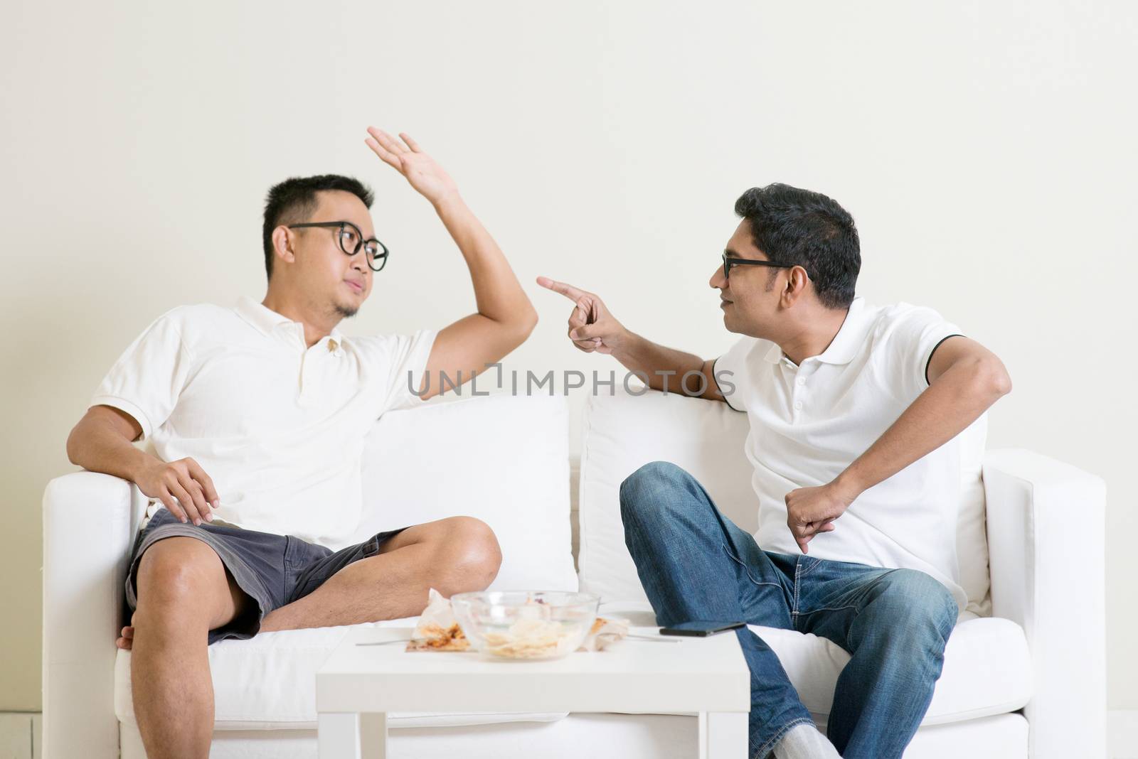 Men talk concept. Two young male friend gathering, chatting and arguing at home. Multiracial people friendship.