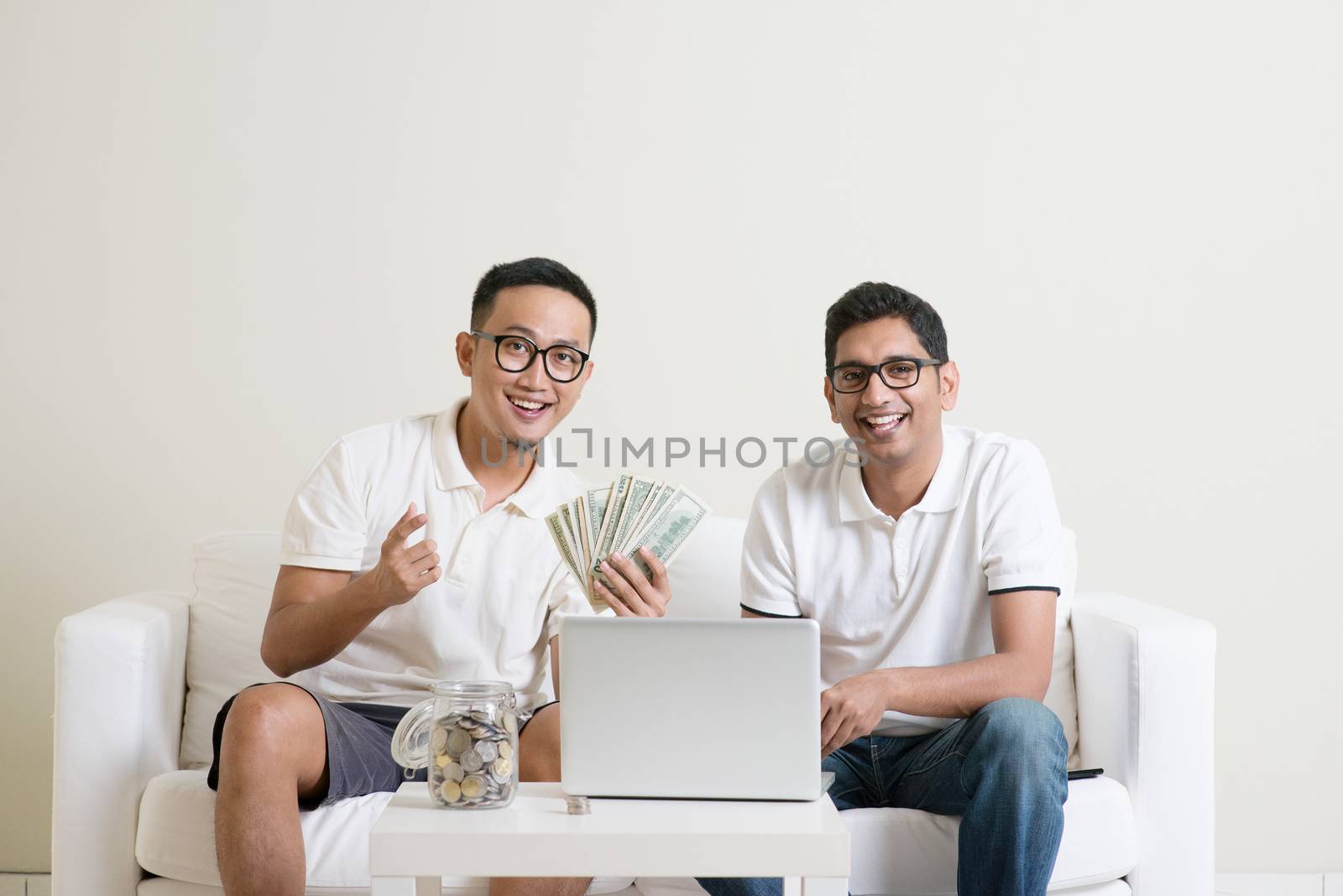 eBusiness concept. Young guys counting cash with partner, earning money from their successful online business. Asian men working from home.