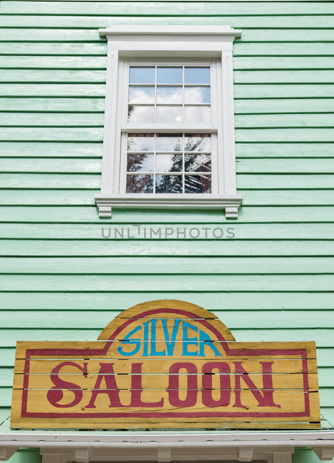 Detail of the facade of a saloon painted green with white windows.