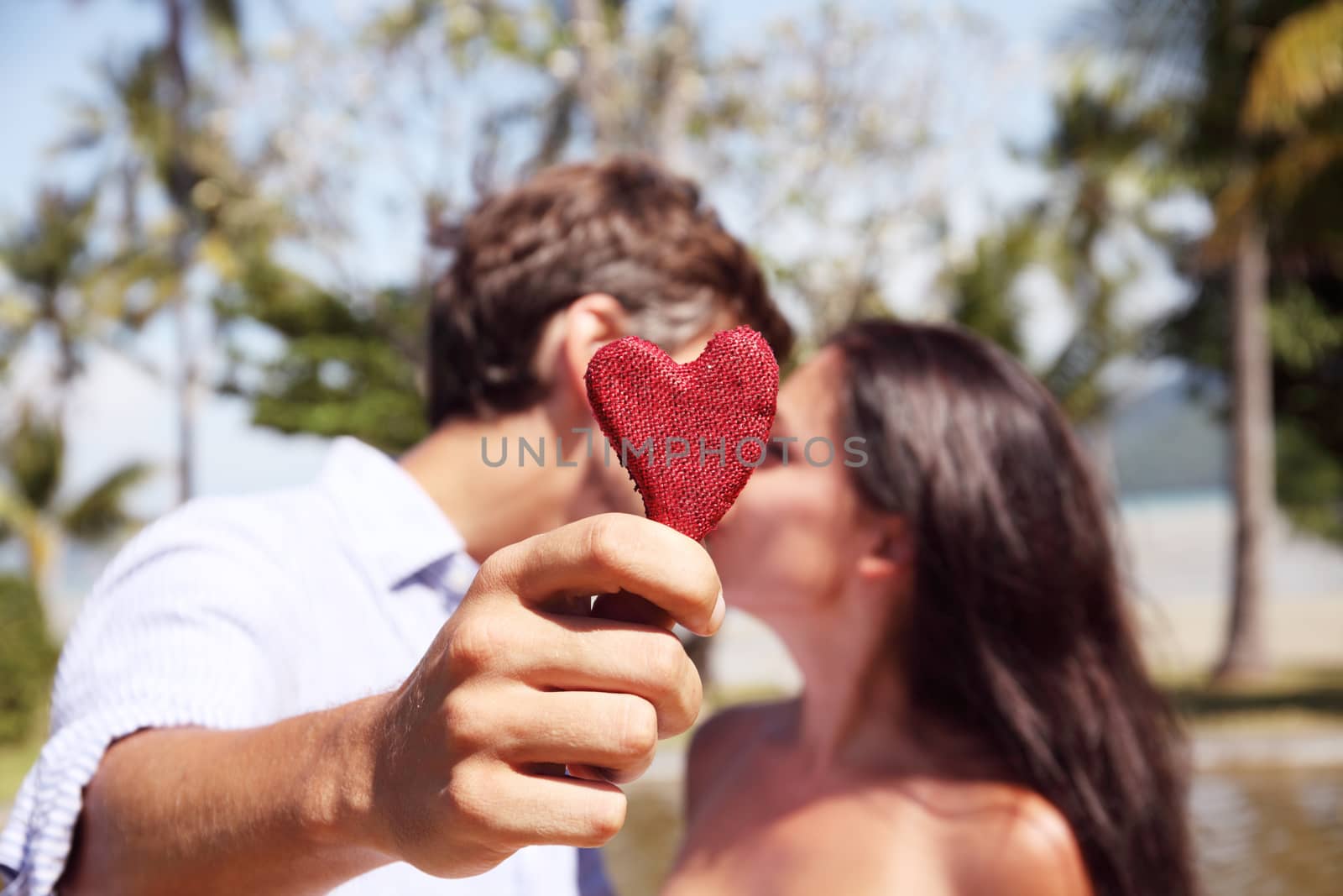 Happy couple kissing behind a red heart