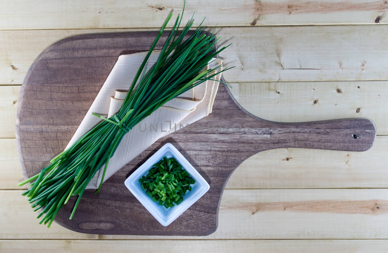 Fresh Chives on Pale Yellow Napkin and Wooden Board by krisblackphotography