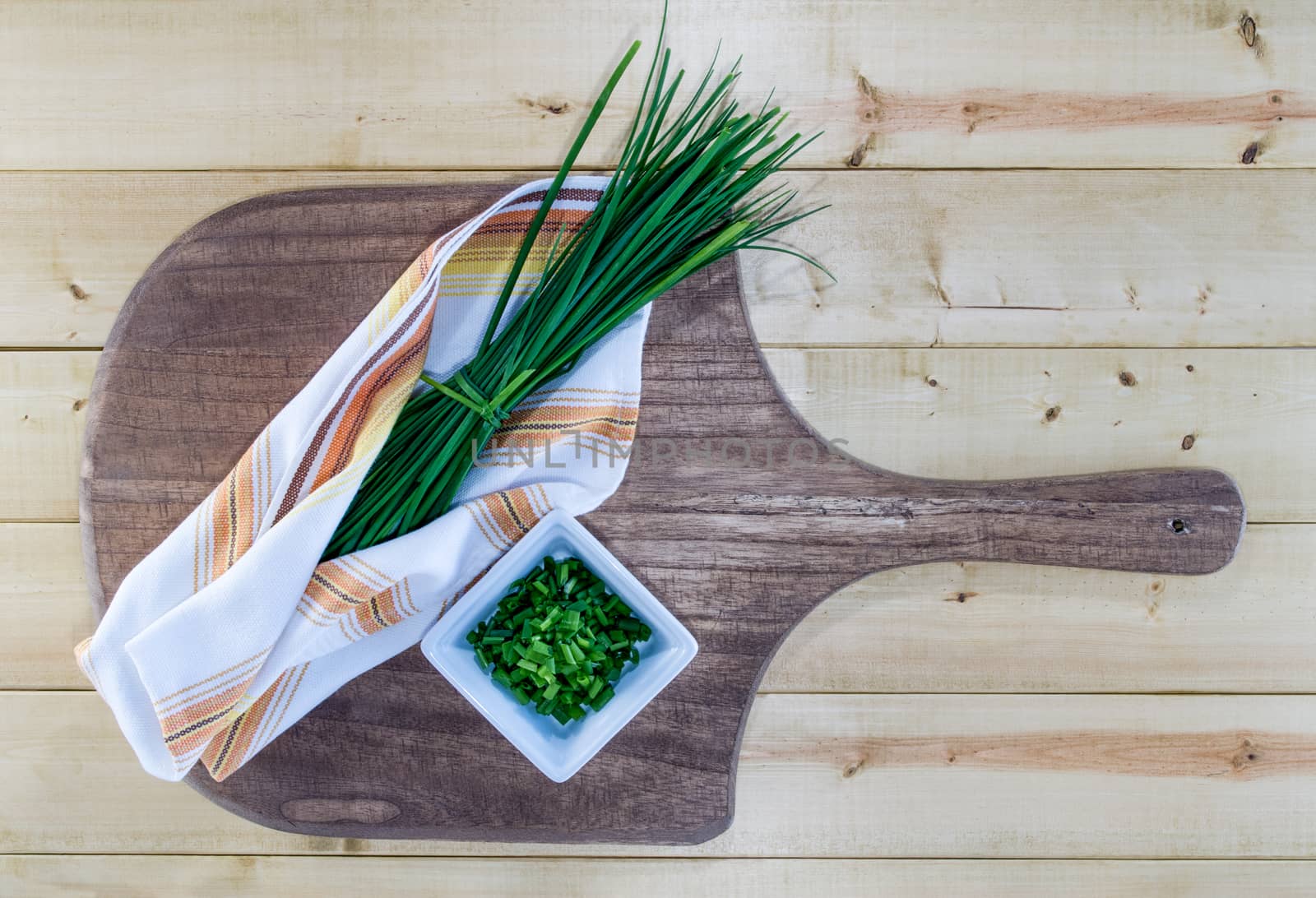 Fresh chives nestled in vintage kitchen towel, on rustic wooden board