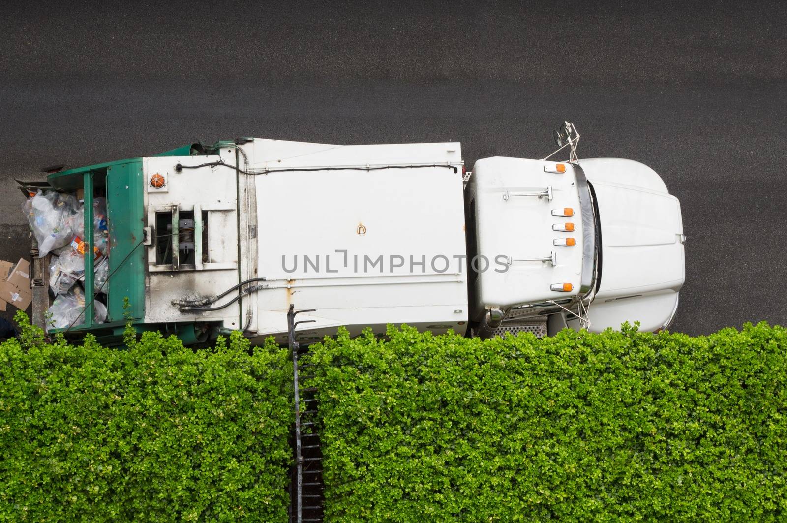 Aerial view of garbage truck parked next to green hedge