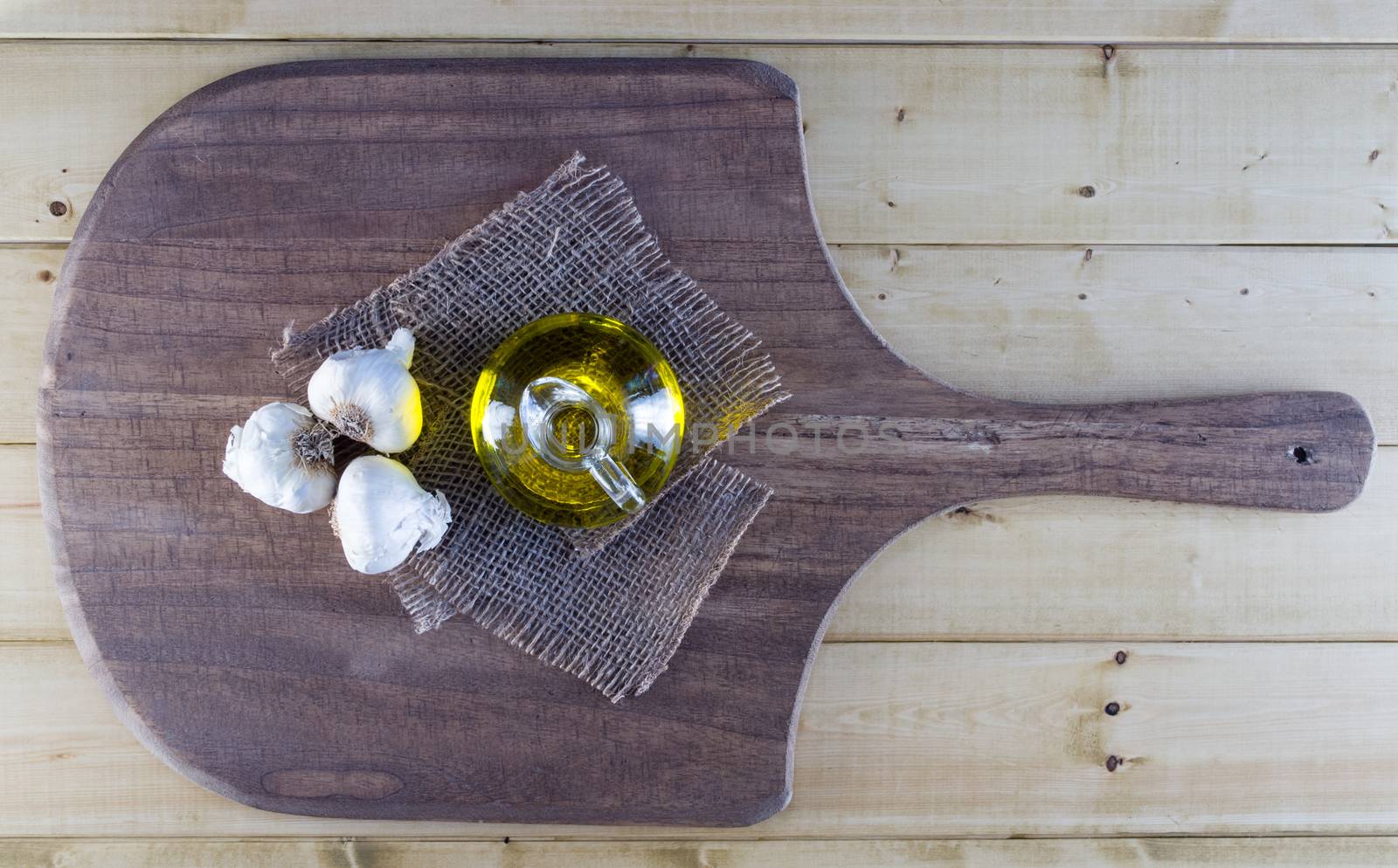 Fresh garlic bulbs and olive oil on rustic board