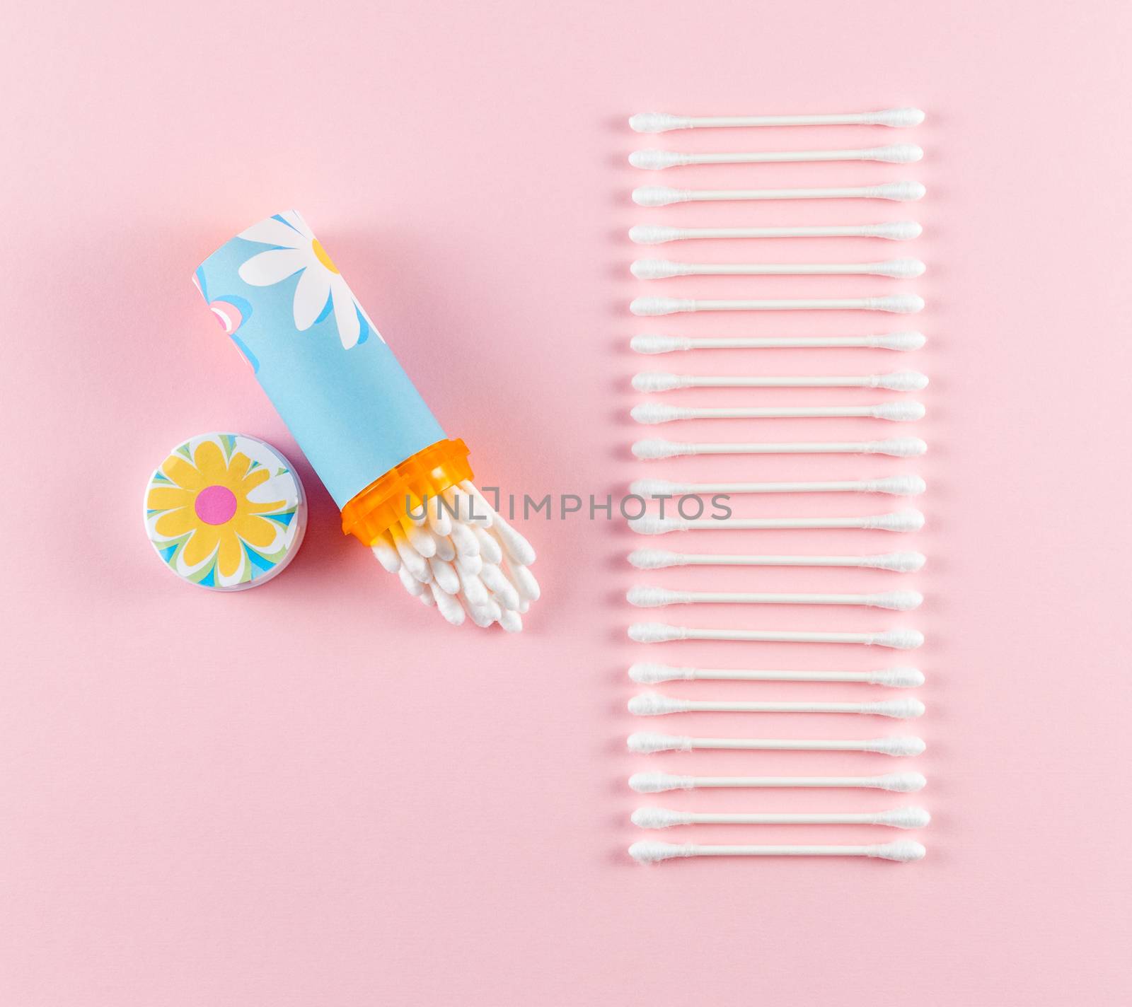 Travel cotton swab holder made from repurposed prescription bottle, on pink background