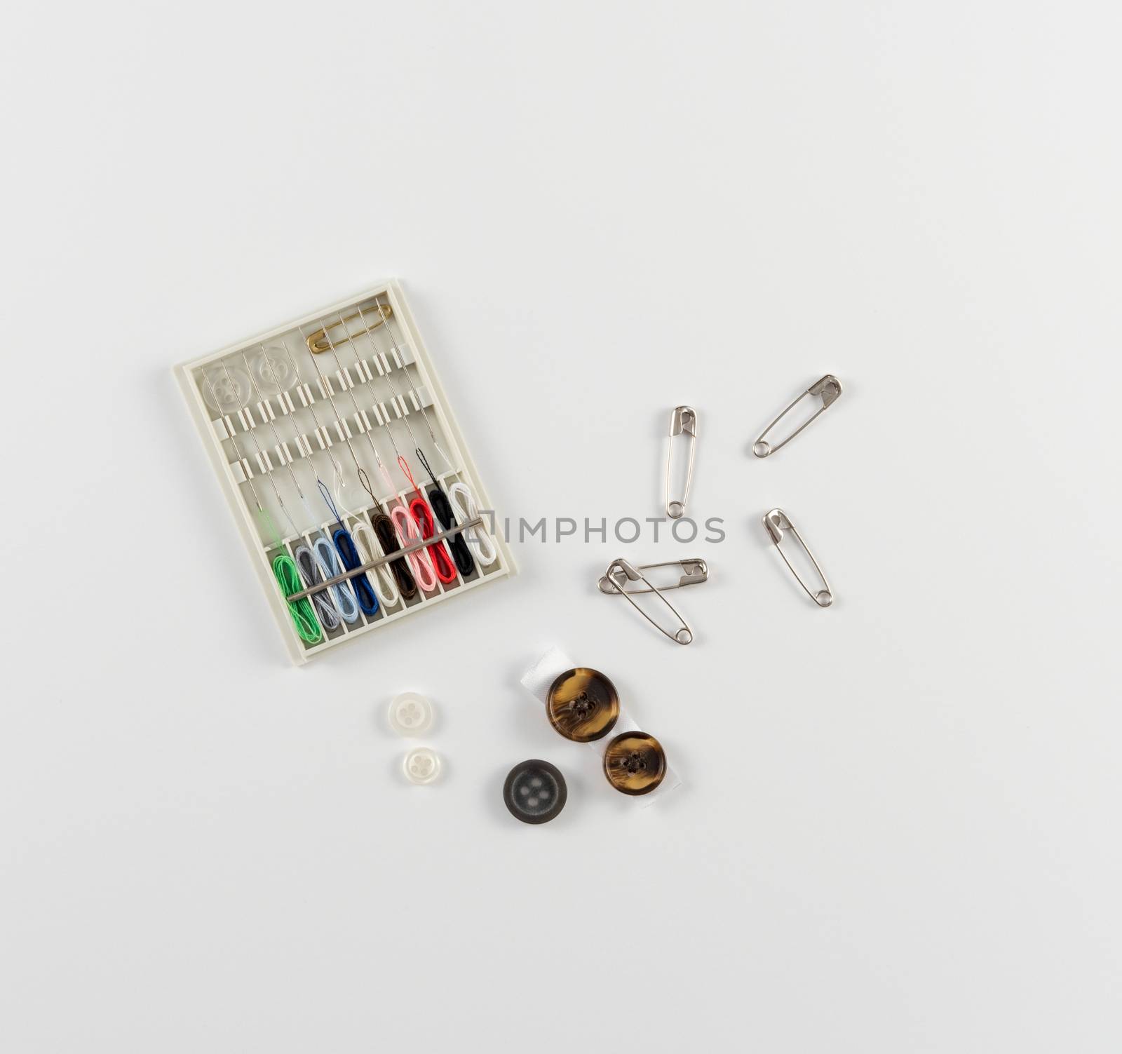 Travel sewing kit with buttons and safety pins, on white background