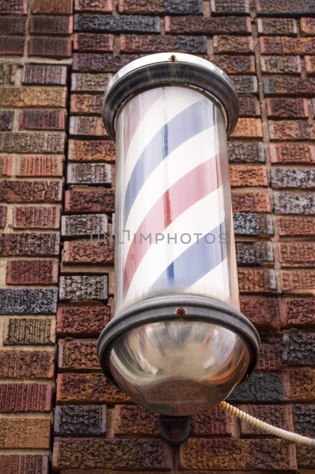 Vintage barber pole mounted on brick wall