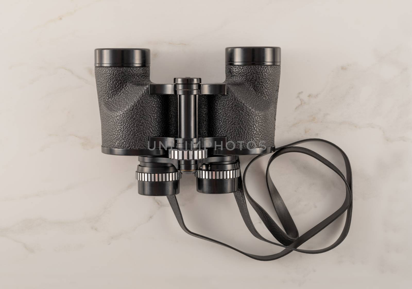 Black vintage binoculars on white marble background