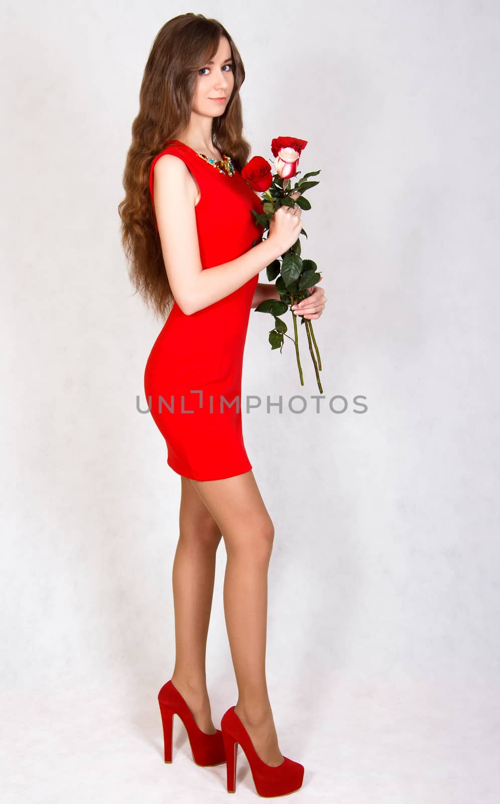 Portrait of a young attractive woman with a bunch of roses over grey background