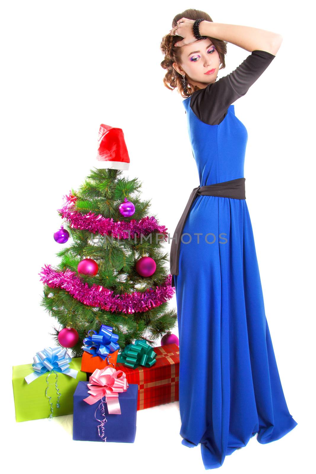 Portrait of a beautiful young woman near the Christmas tree and presents isolated over white background