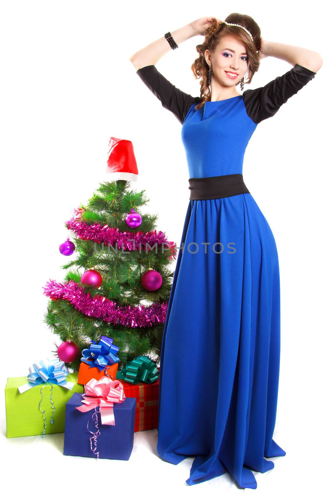 Portrait of a beautiful young woman near the Christmas tree and presents isolated over white background