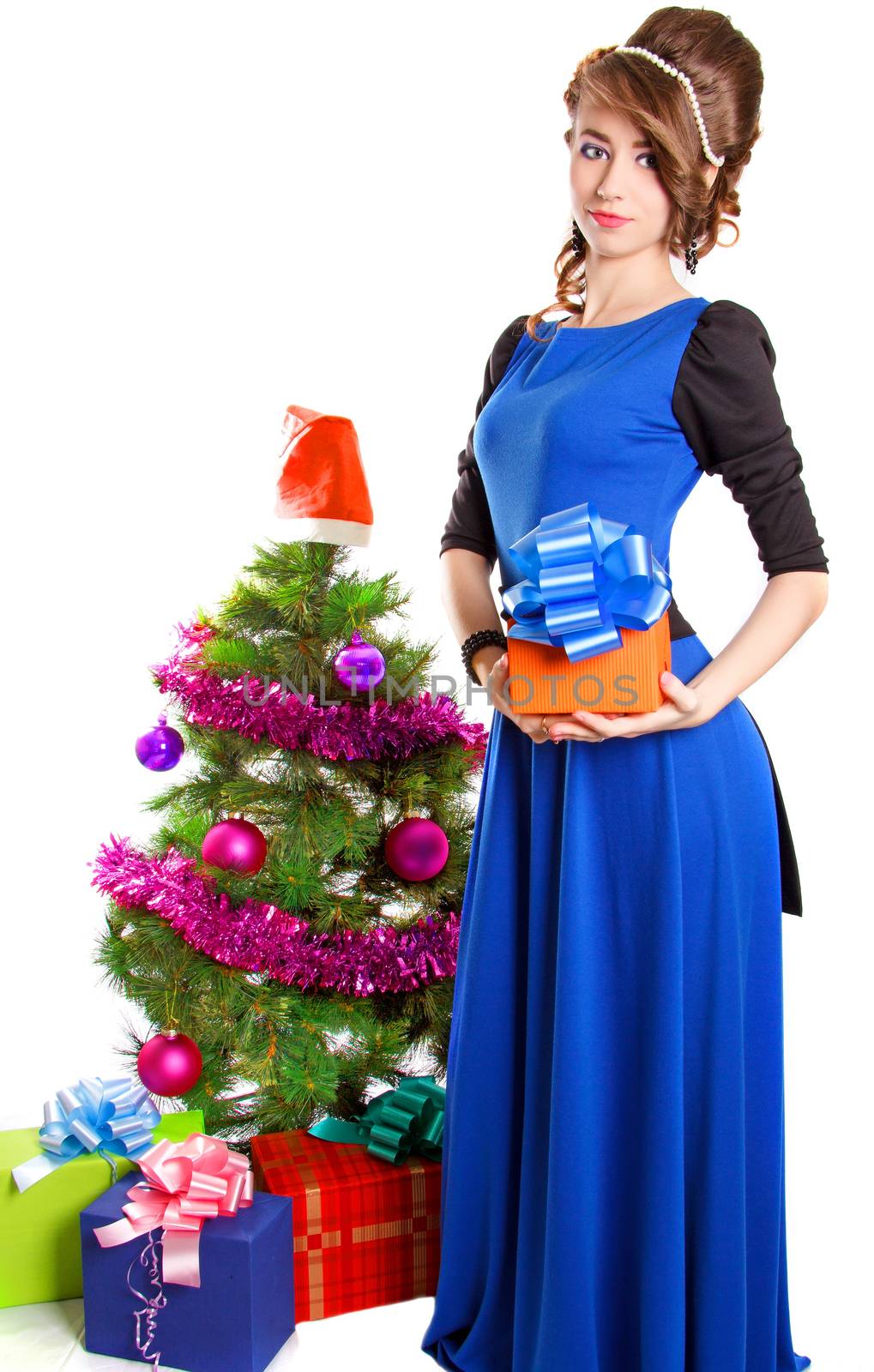 Portrait of a beautiful young woman holding a present near the Christmas tree isolated over white background