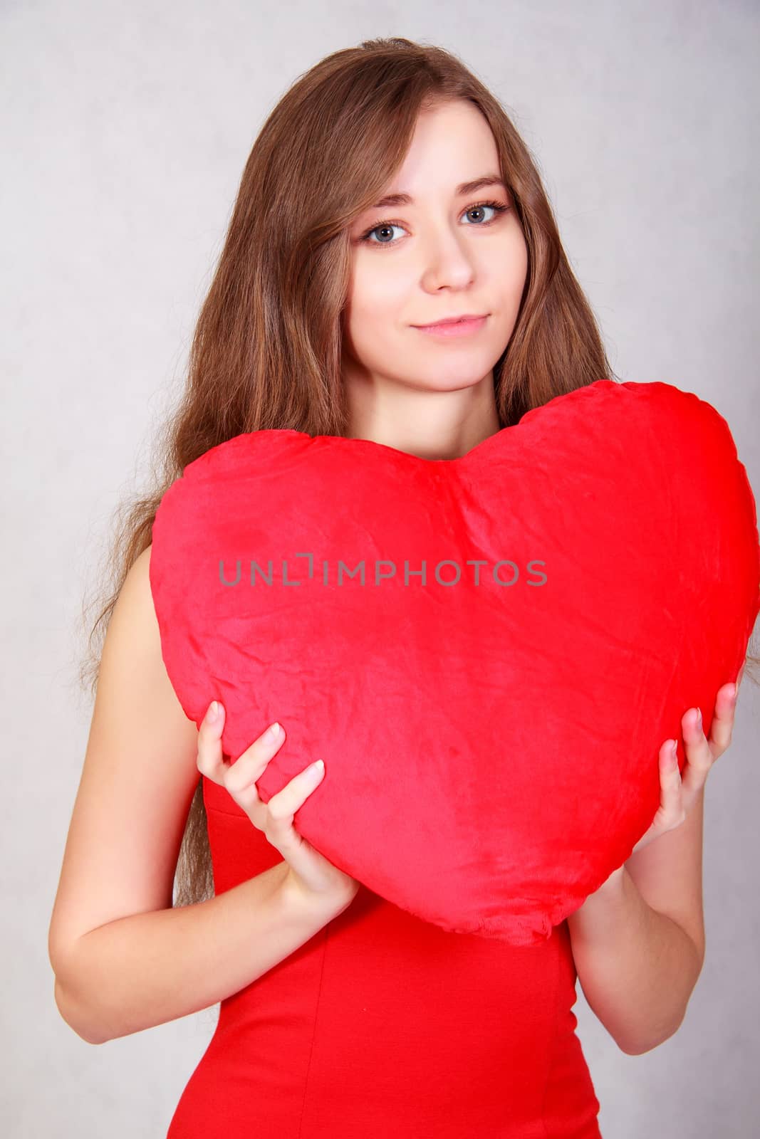 Portrait of a young attractive woman with a heart-shaped pillow by Artzzz