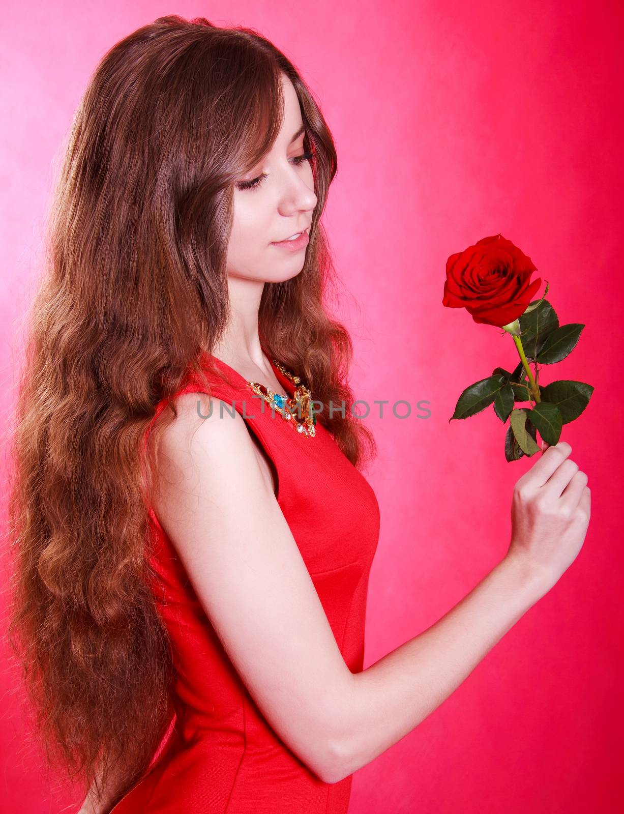 Beautiful young woman with a red rose over pink background