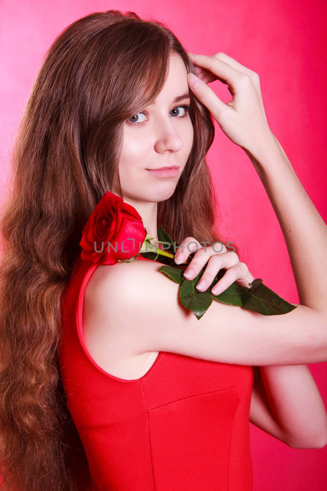 Beautiful young woman with a yellow rose over pink background