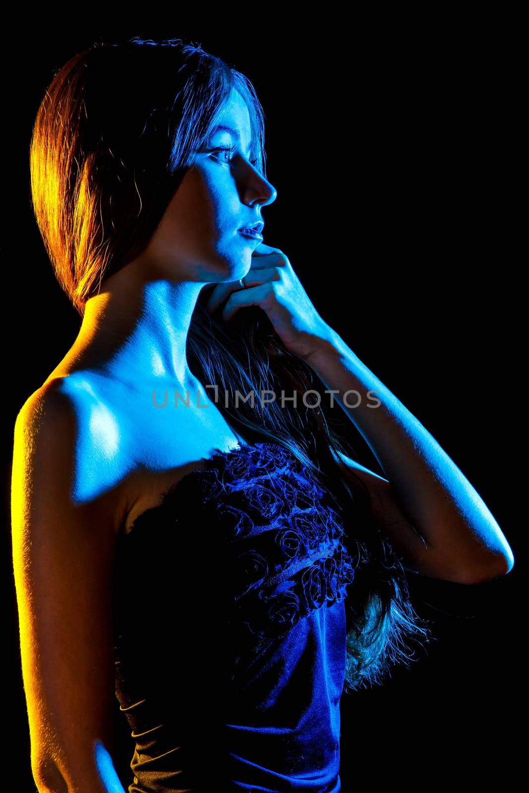 Beautiful young woman in blue and yellow lights over black background