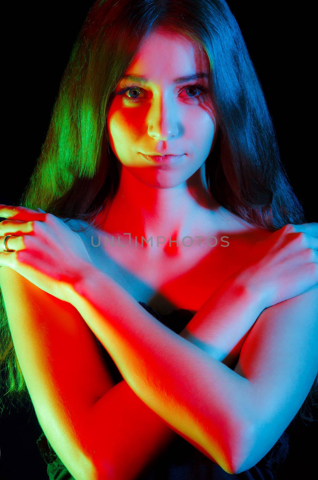 Beautiful young woman in red, green and blue lights over black background