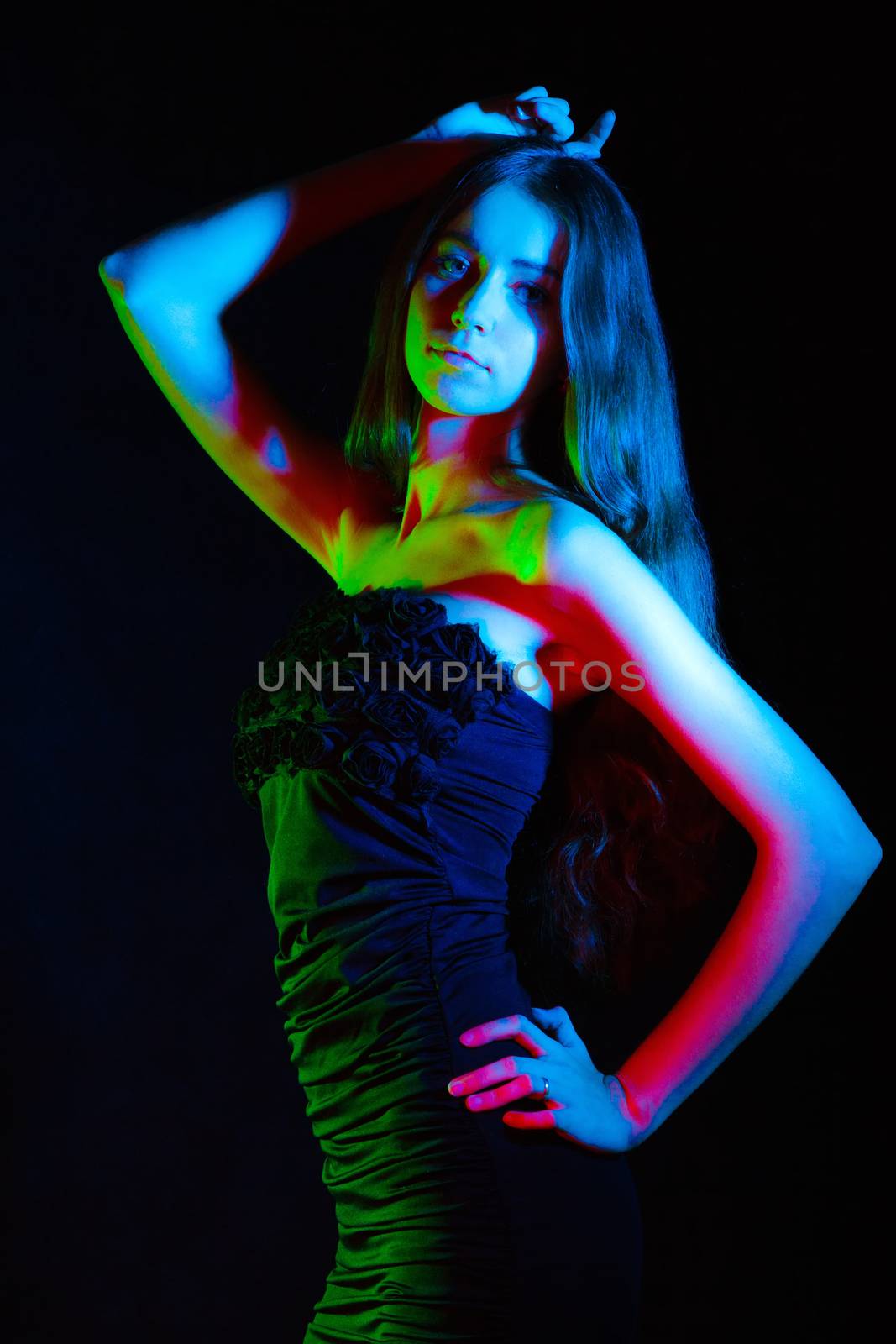 Beautiful young woman in red, green and blue lights over black background