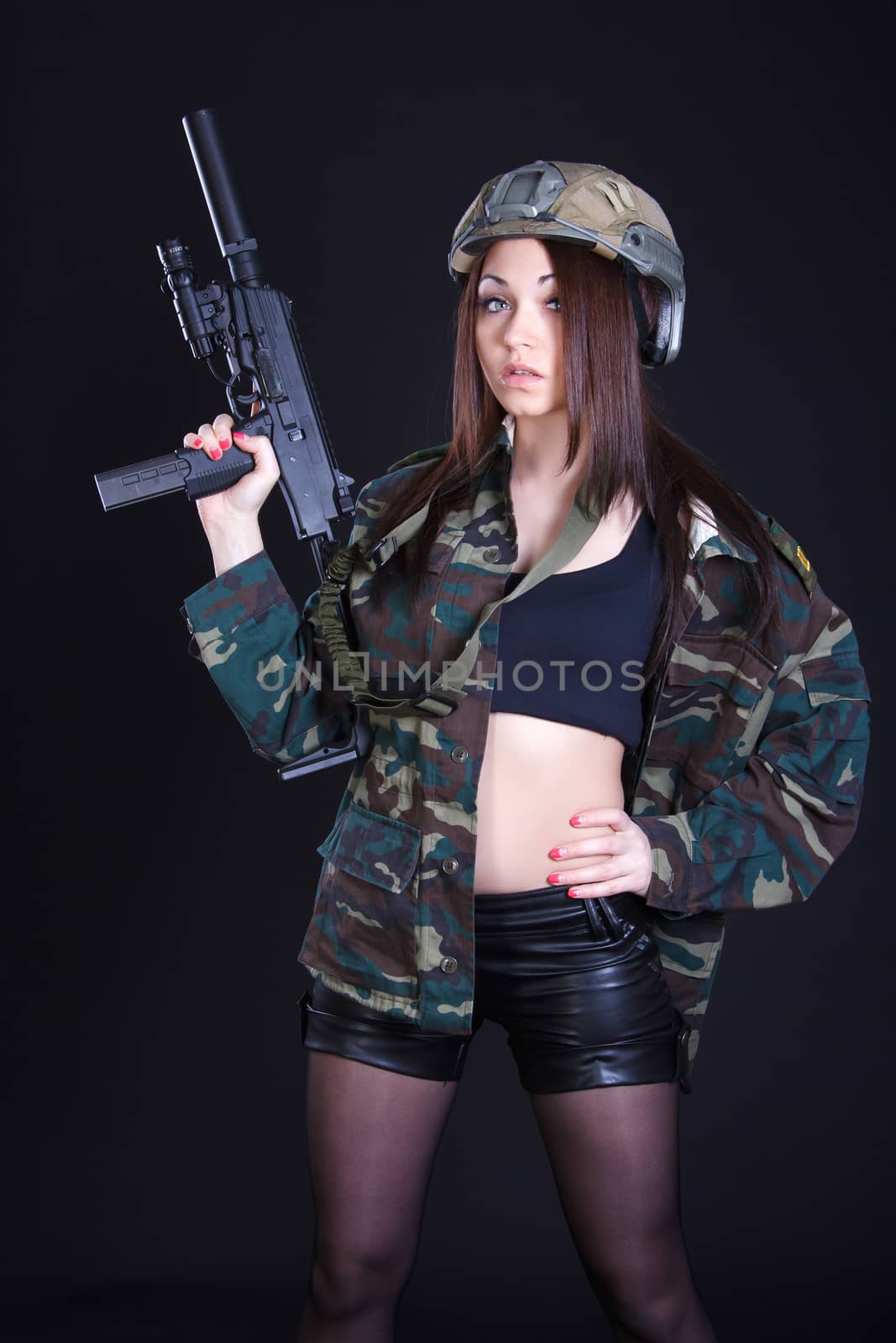 Portrait of a woman in a military uniform with a submachine gun over black background
