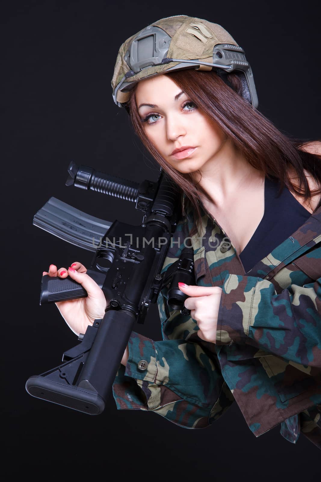 Woman in the military uniform with an assault rifle on the shoulder over black background