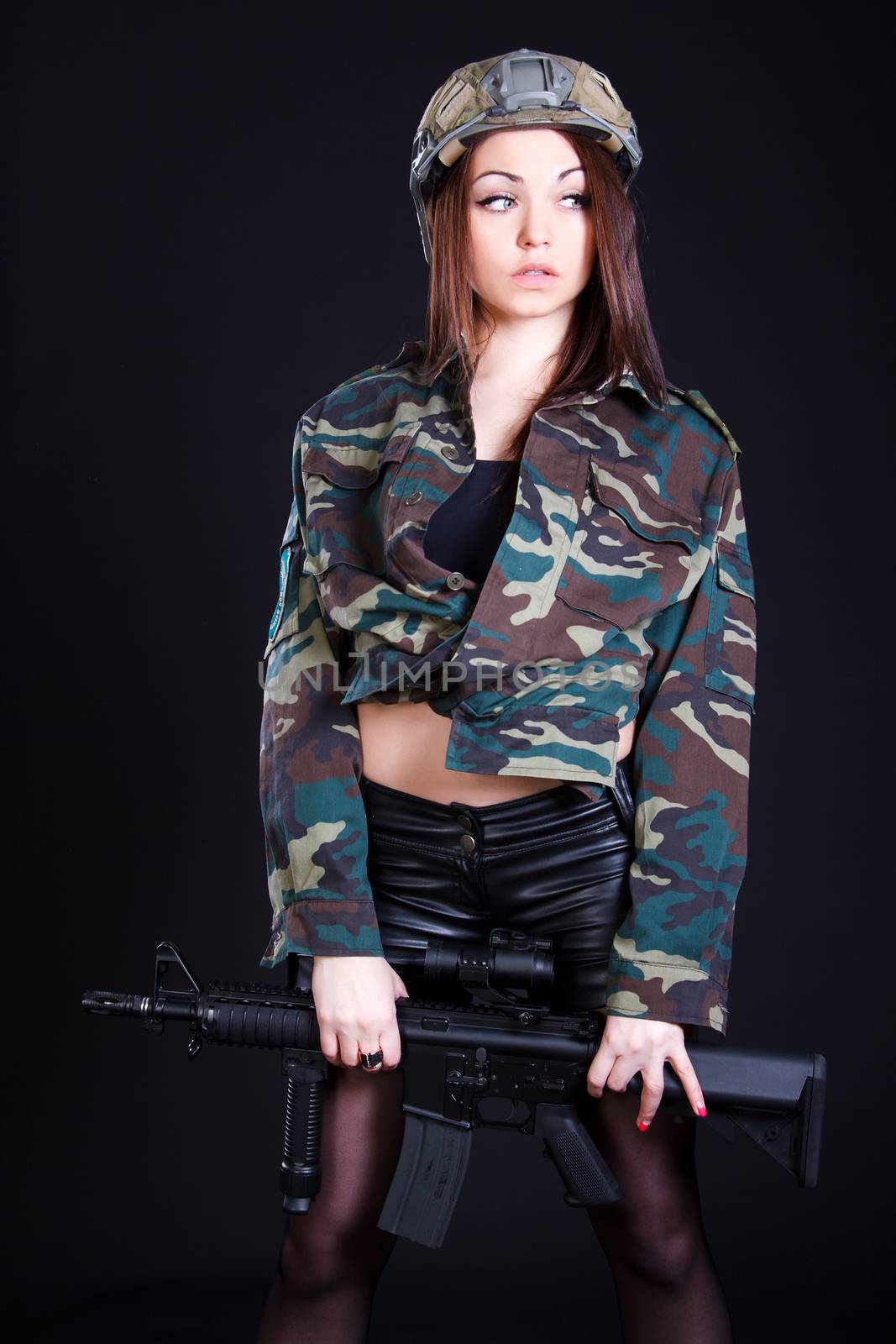 Woman in the military uniform with an assault rifle over black background