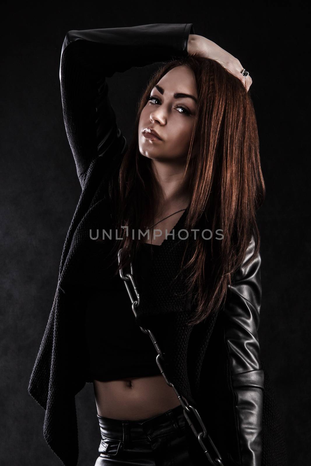 Beautiful young woman with a chain over black background