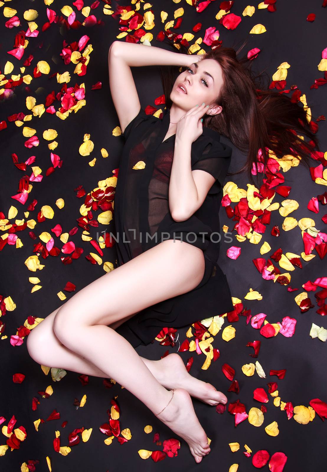Beautiful young woman laying on sparse rose petals by Artzzz