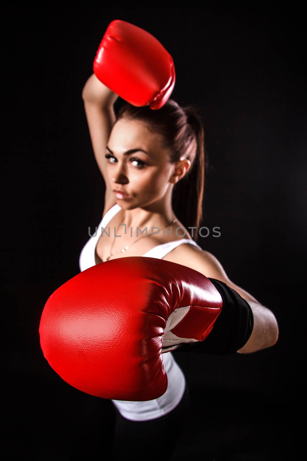 Beautiful young woman in a red boxing gloves over black background (focus is on the glove)