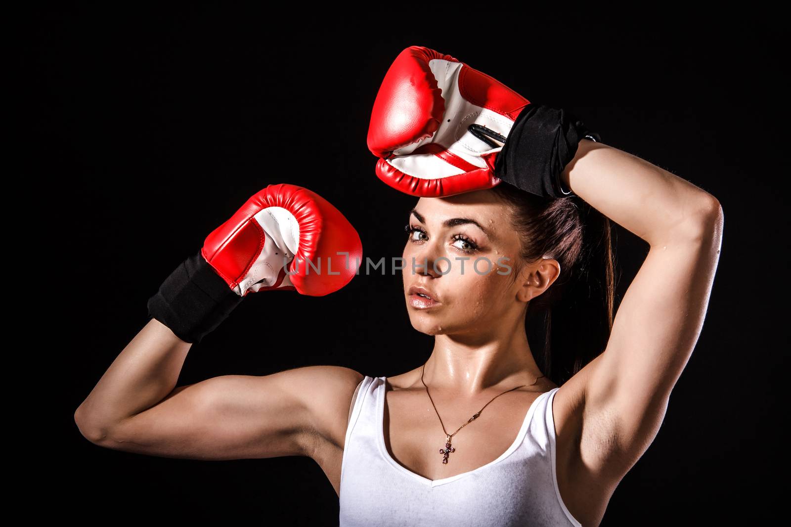 Beautiful young woman in a red boxing gloves over black background