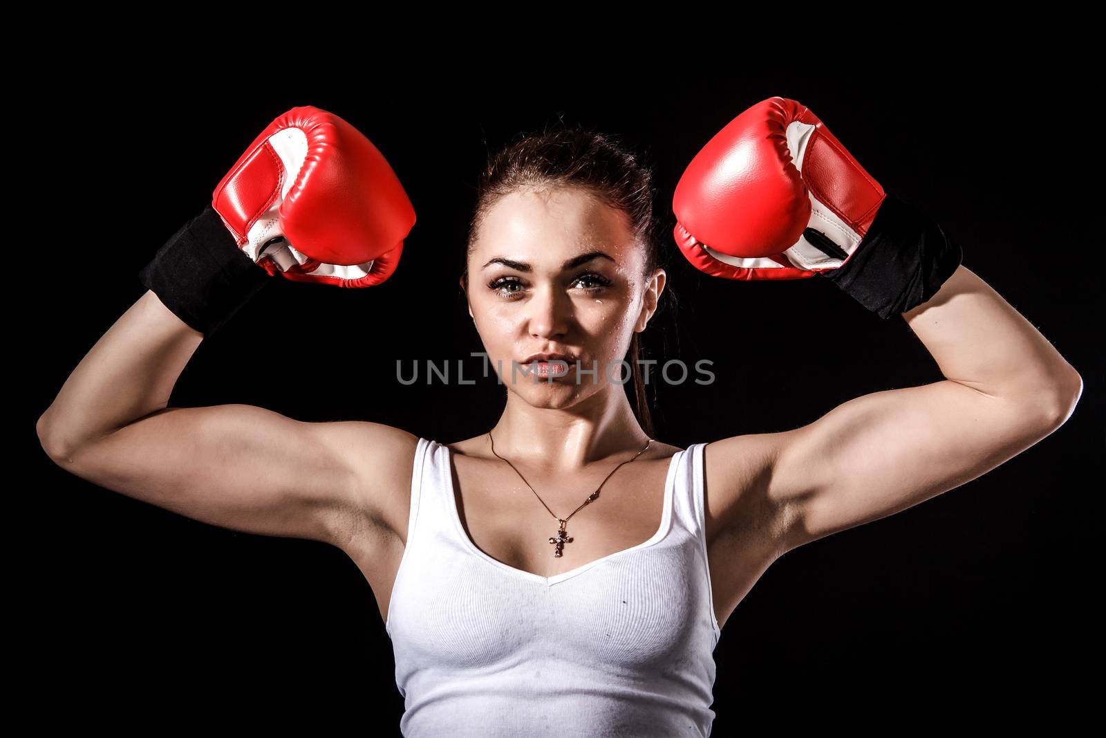 Beautiful young woman in a red boxing gloves over black background