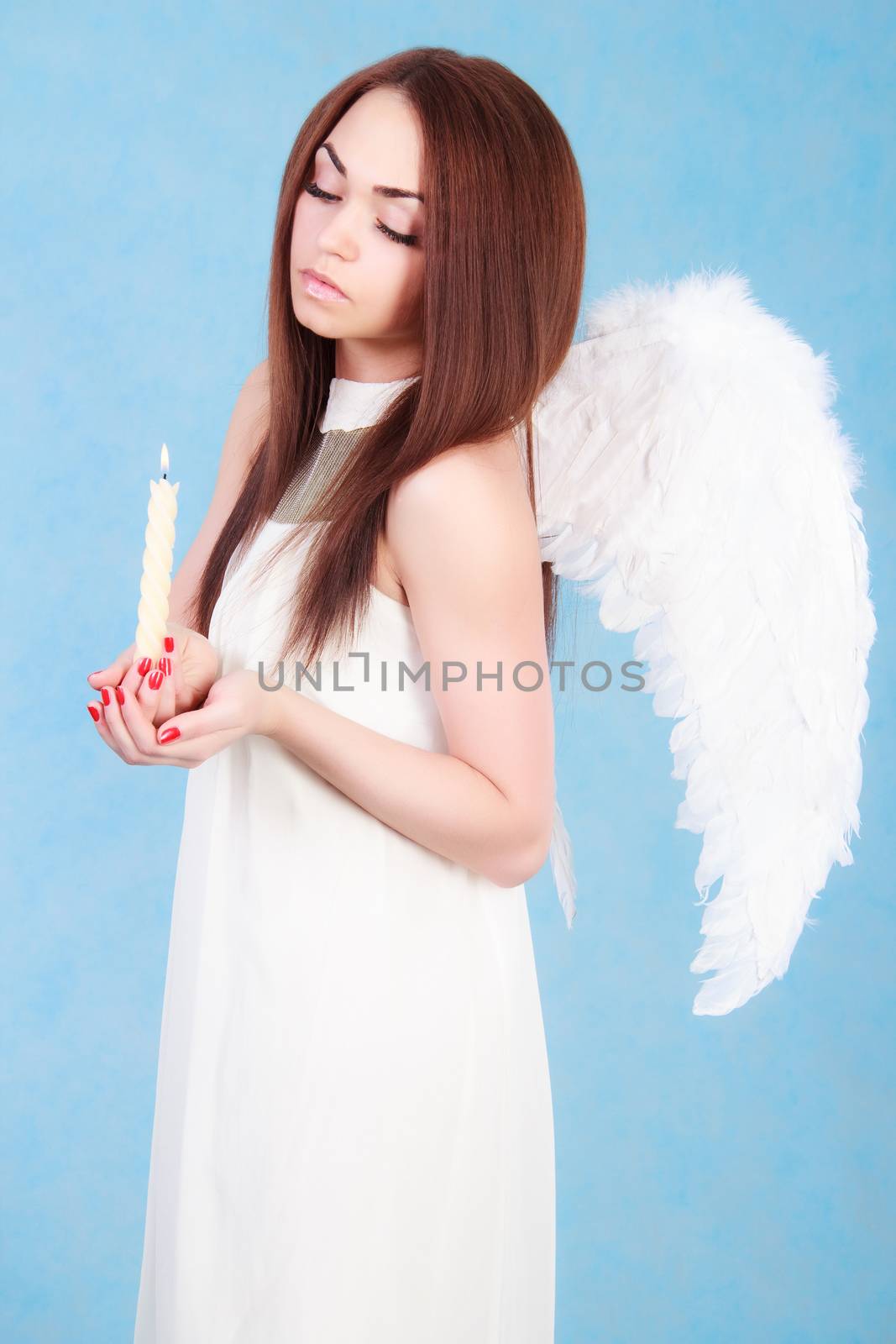 Beautiful young angel with a candle over cyan background