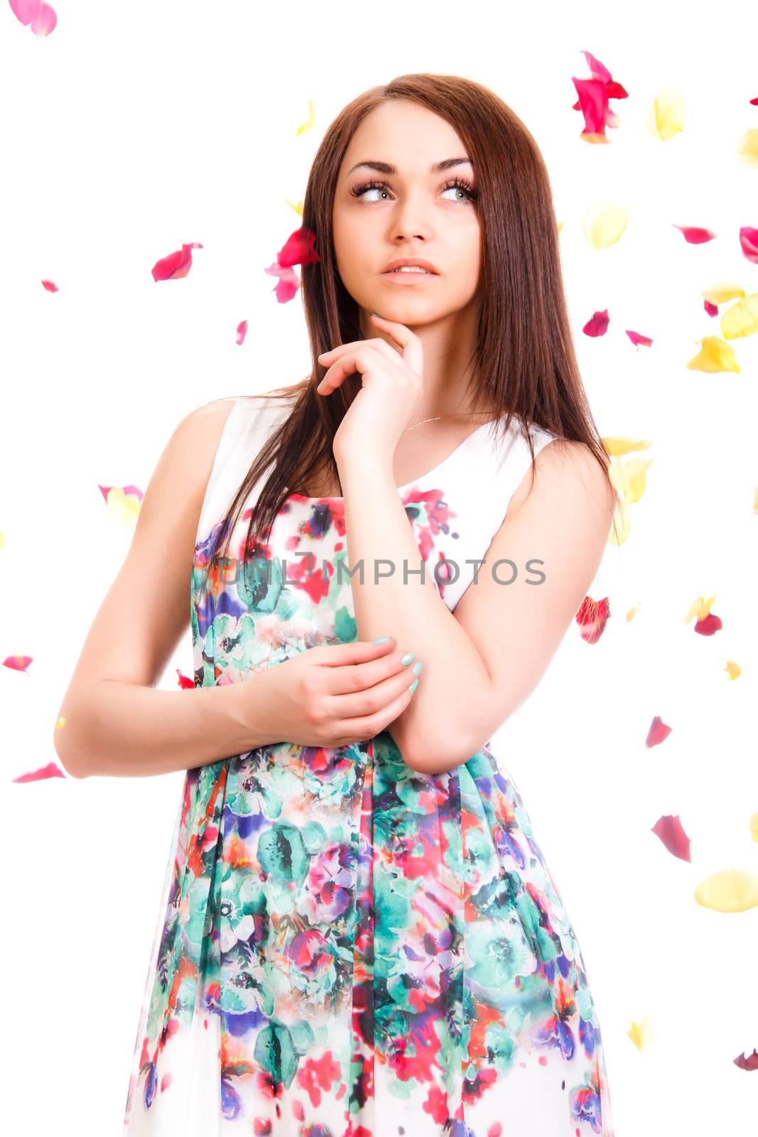 Portrait of a pretty young woman in a bright dress isolated over white background with pink and yellow falling petals