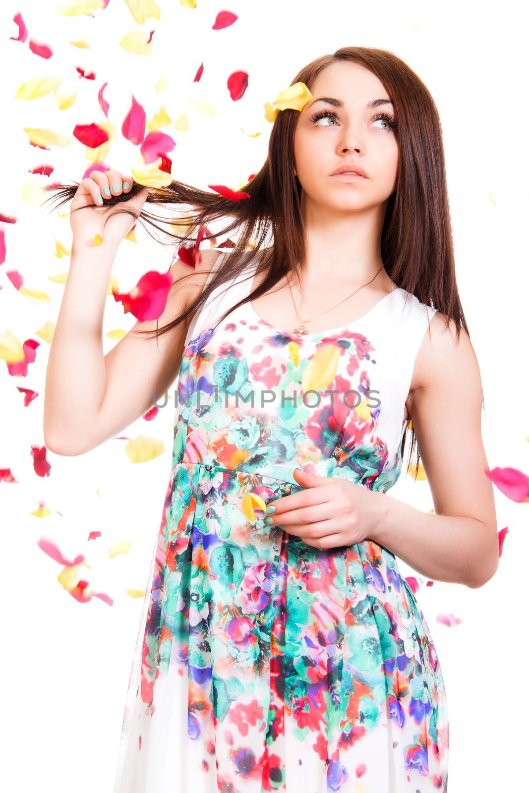Portrait of a pretty young woman in a bright dress isolated over white background with pink and yellow falling petals