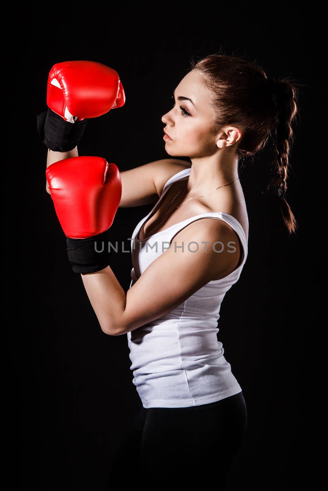 Beautiful young woman in a red boxing gloves over black background