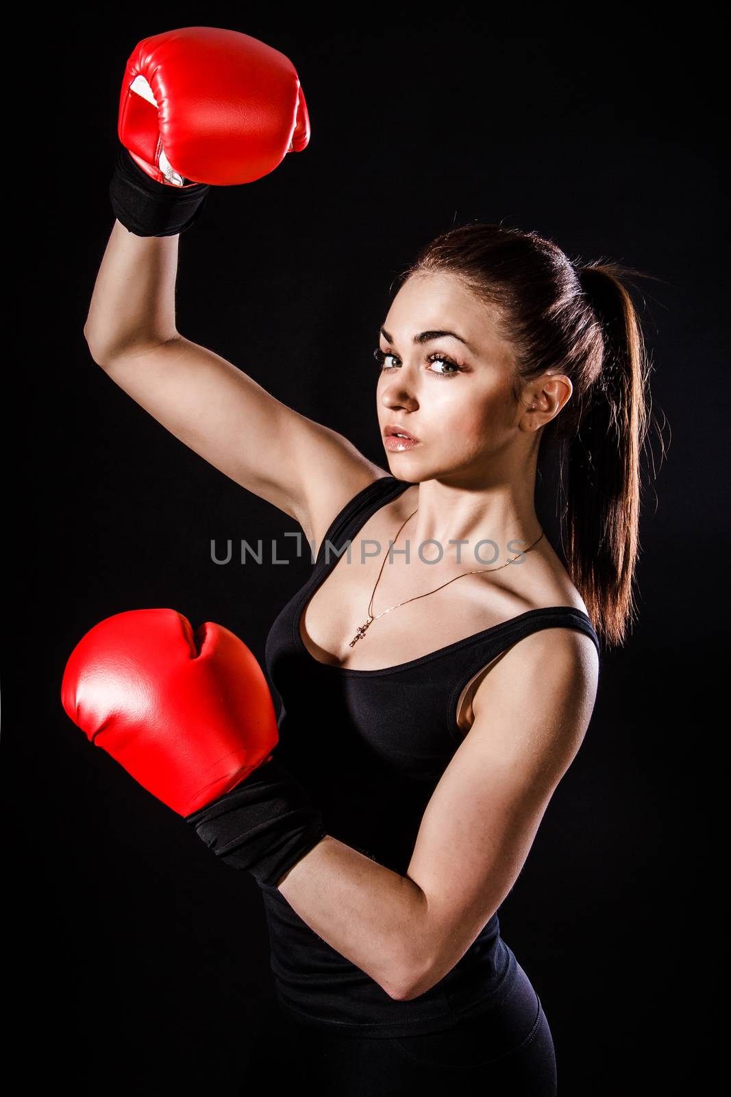 Beautiful young woman in a red boxing gloves over black background