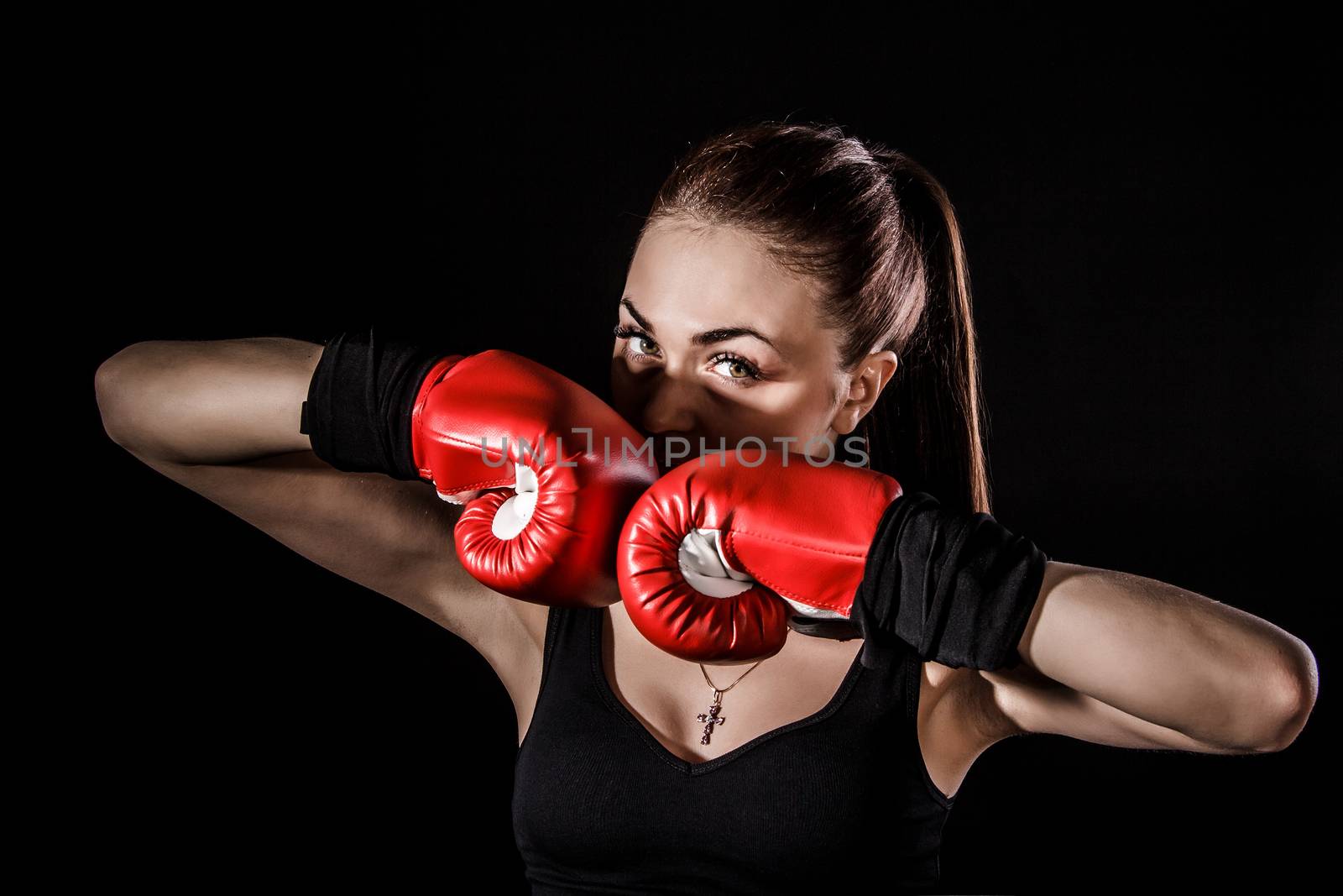 Beautiful young woman in a red boxing gloves over black background