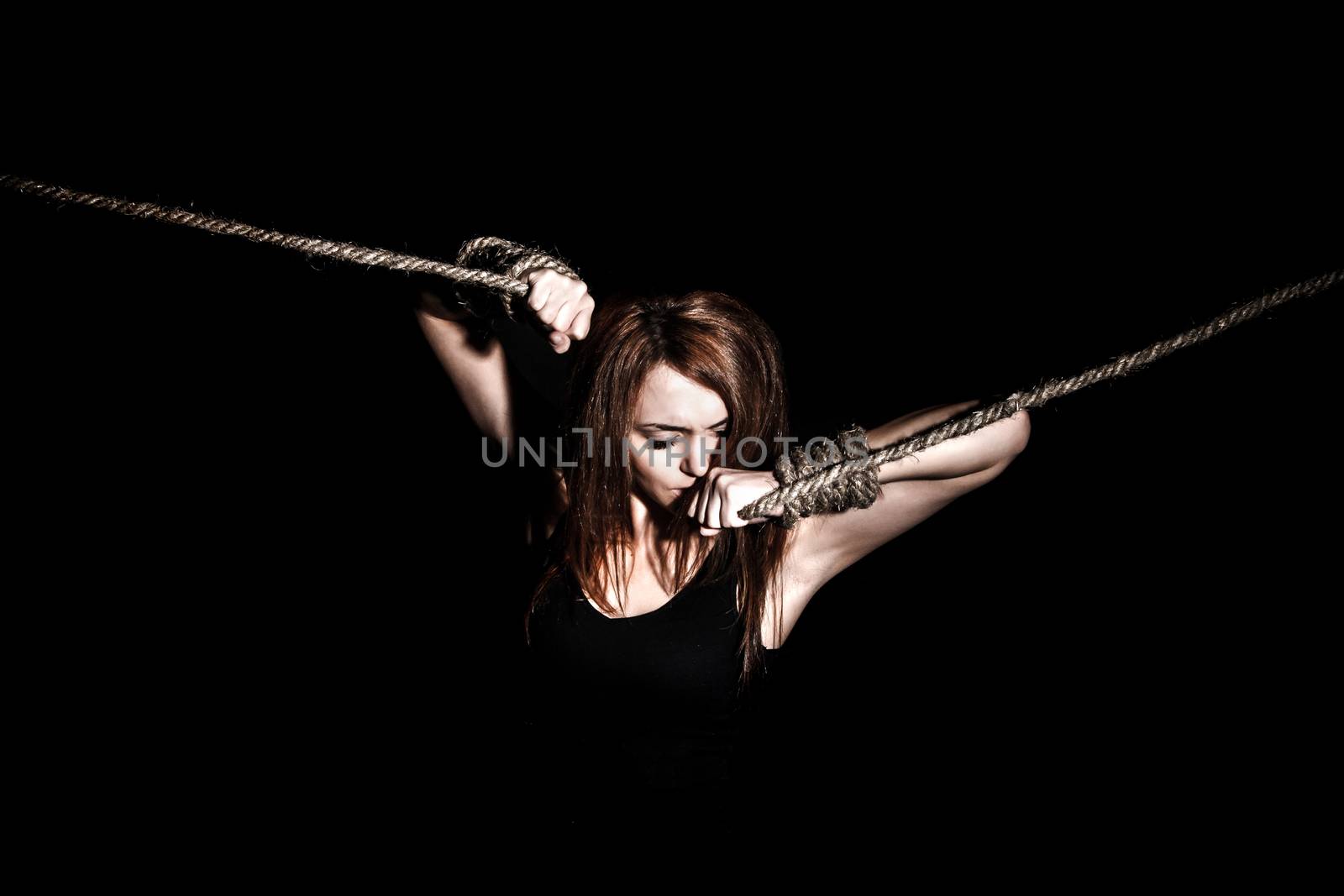 Beautiful young woman with tied arms over black background