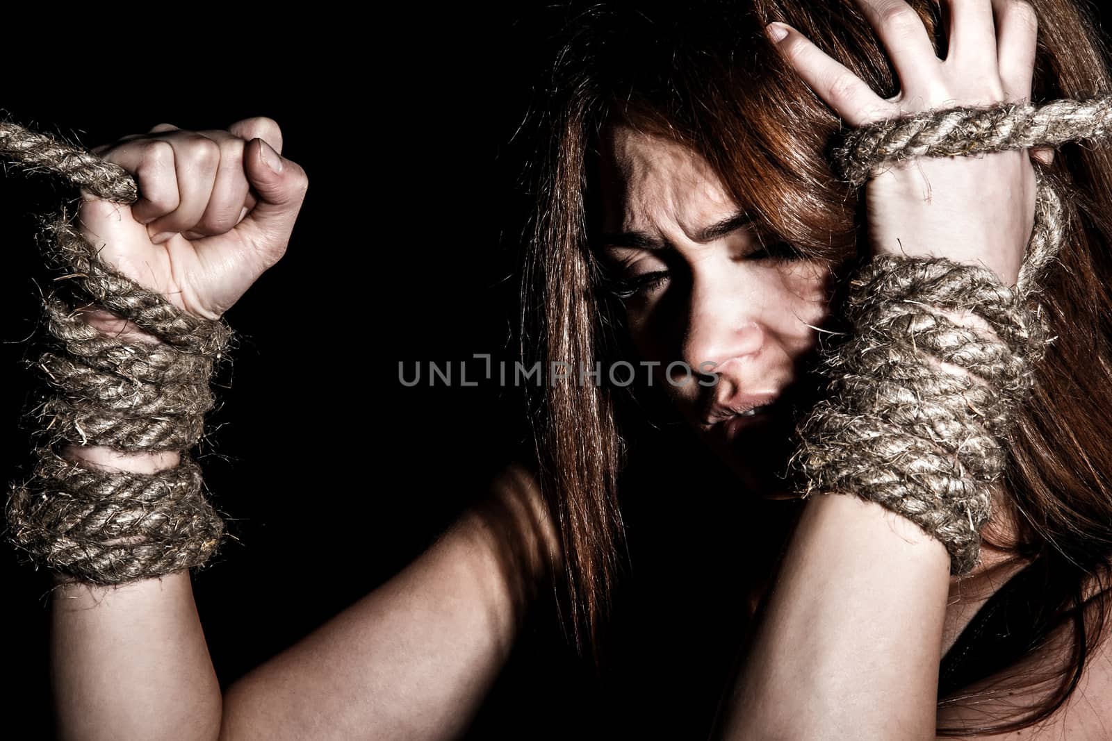 Beautiful young woman with tied arms over black background