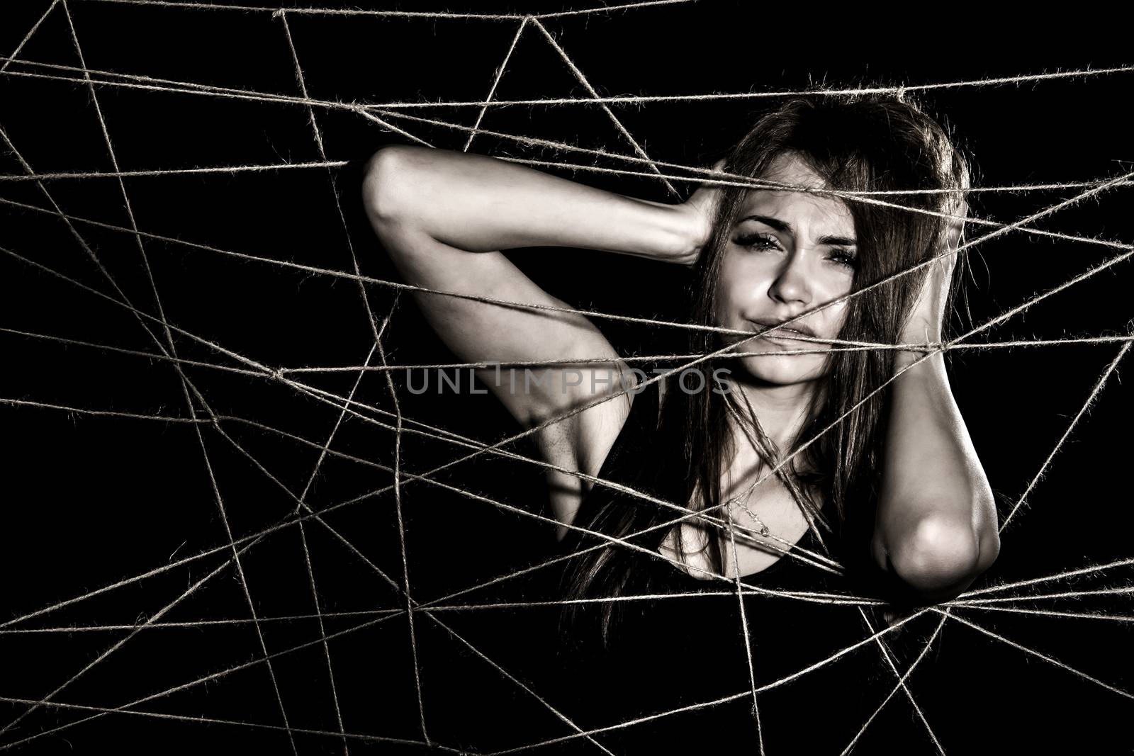Young woman entangled the net of ropes over black background