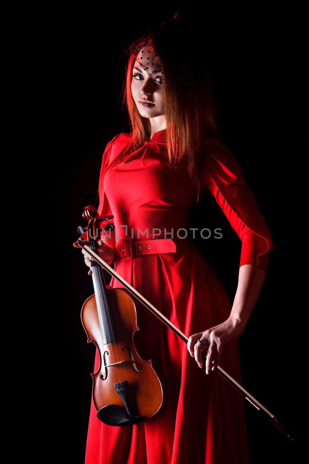 Pretty young woman holding a violin over black background