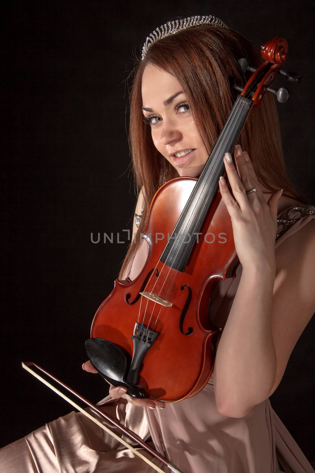 Pretty young woman holding a violin over black background